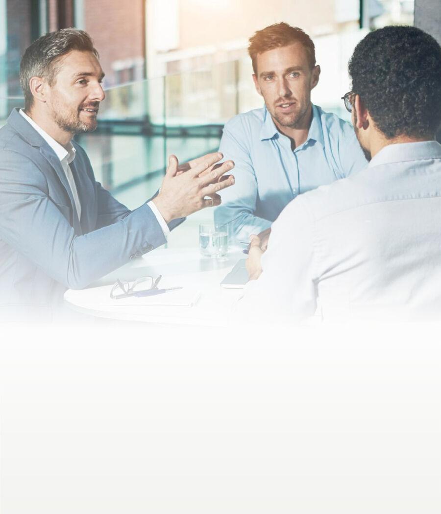 Three professionals discussing a new product idea around a table in a bright modern office